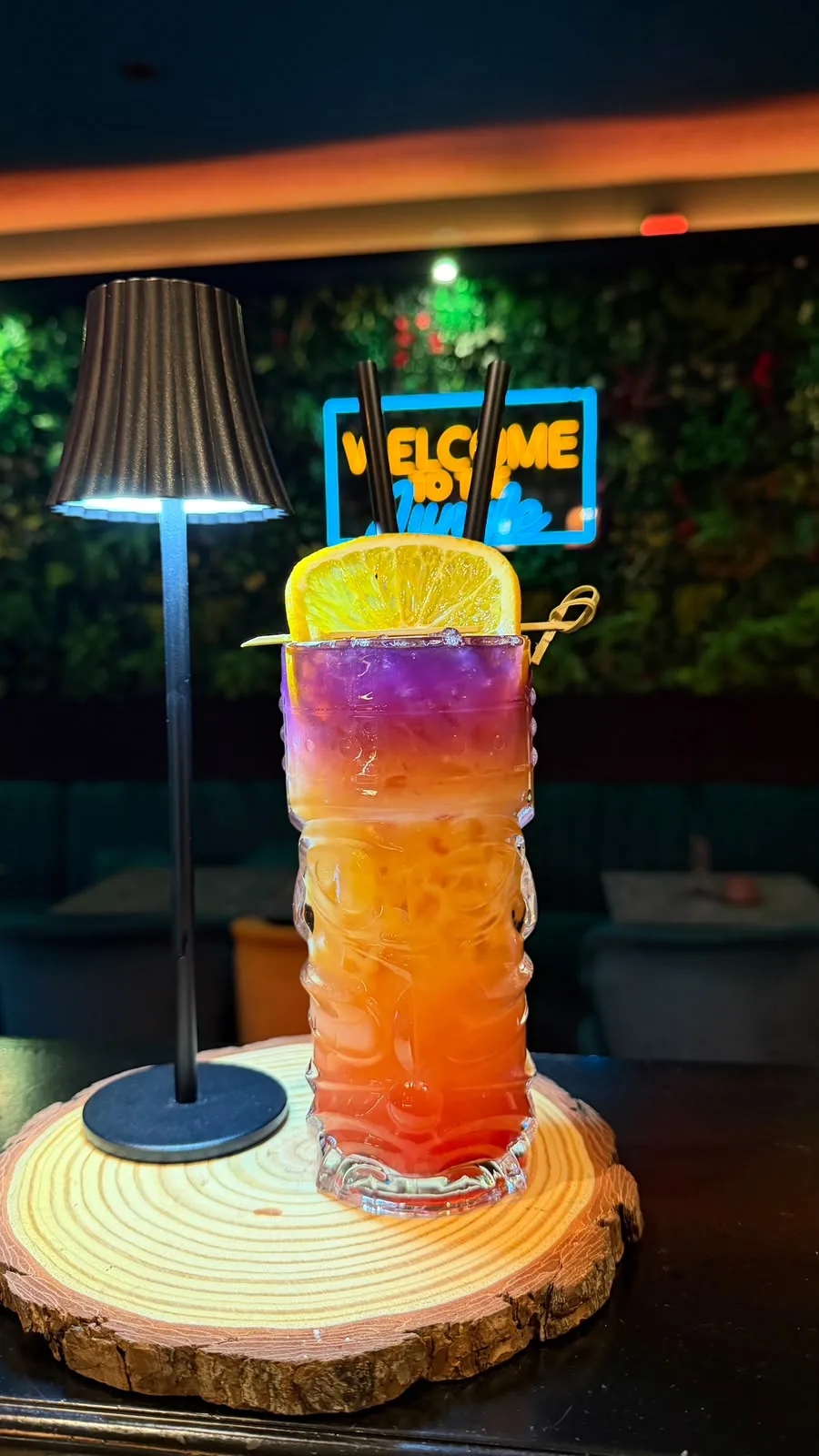 GTA Cocktail im Tiki-Glas mit Farbverlauf von Lila über Orange bis Rot und Orangenscheibe in der Jungle Bar Radolfzell
